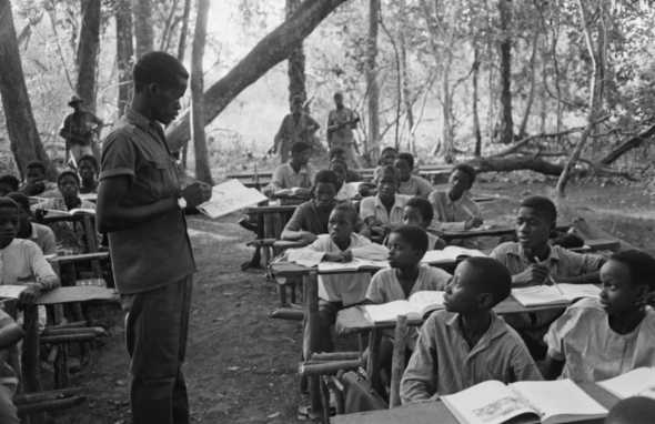 A teacher talks to his pupils at a guarded outdoor classroom during the Portuguese Colonial War, Guinea-Bissau, West Africa, 1972 [Reg Lancaster/Express/Hulton Archive/Getty Images]