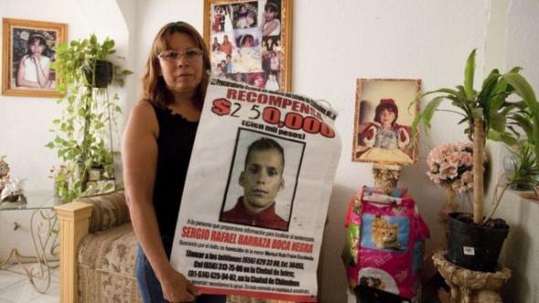 Marisela Escobedo com um cartaz de recompensa por informações sobre Sergio Barraza.