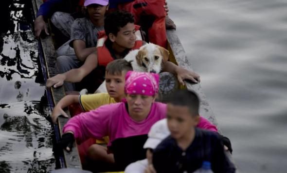 Joshua Morales viaja com o seu cão Toby ao colo num barco de migrantes, depois de cruzar a pé o Darién desde a Colombia (Natacha Pisarenko AP)