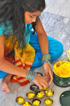 uma jovem hindu prepara velas artesanais antes de uma cerimónia religiosa no templo de Maputo