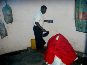 Eng Job Massinge, administrando um bafo a um paciente. Segura na mão o tchova, instrumento essencial do kufemba de xizingo (foto de Cremildo Binana)